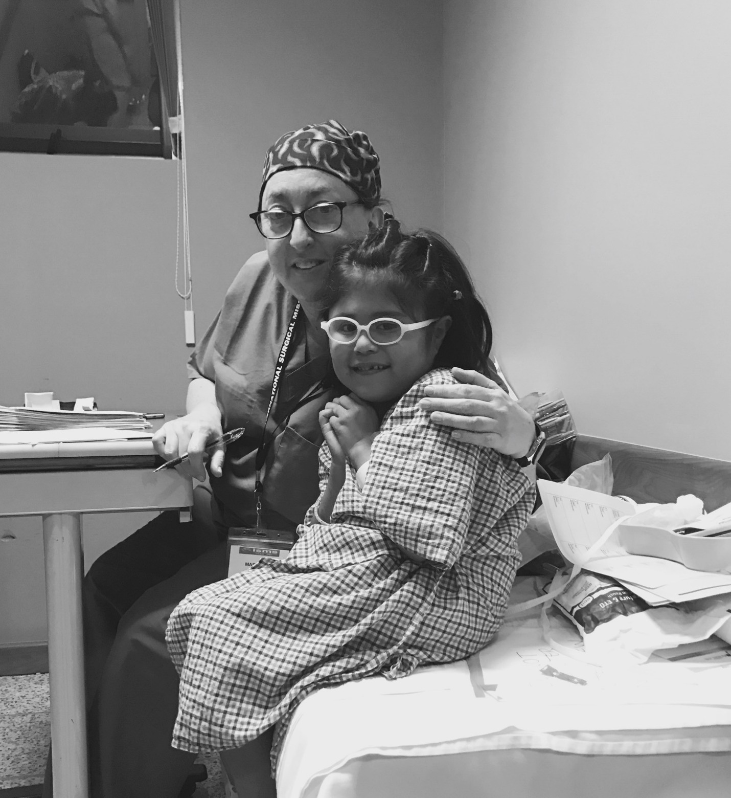 Marcia Levine in scrubs with her arm around a young patient