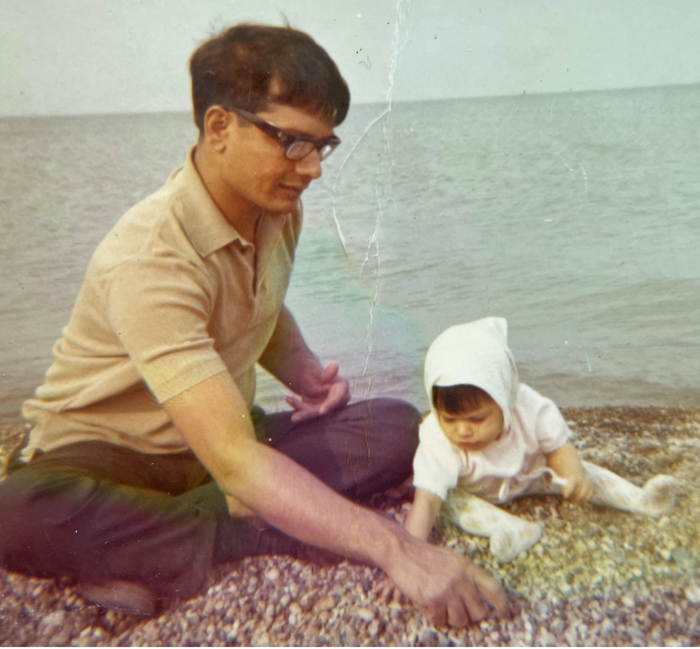 Old photo of a man with a baby on a beach