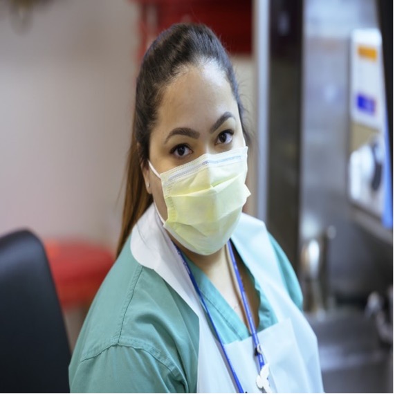 MSK Colleague in scrubs and apron sat by computers