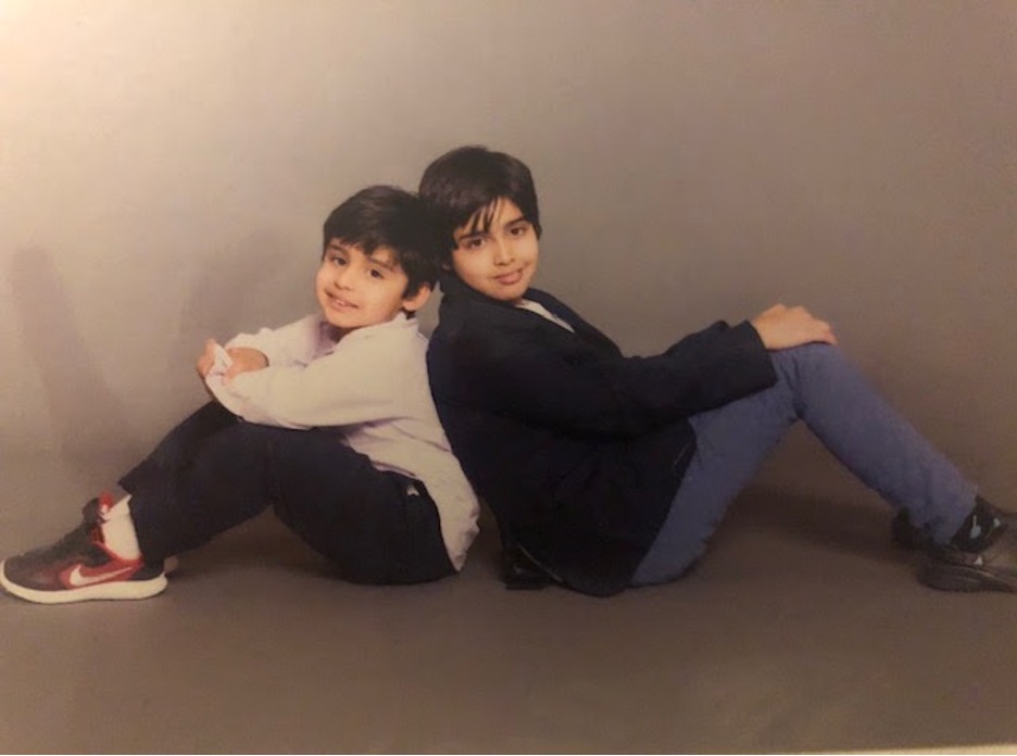 Two children sat with their backs together