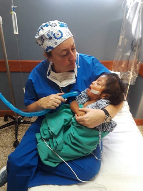 Marcia Levine in scrubs cradling a poorly child